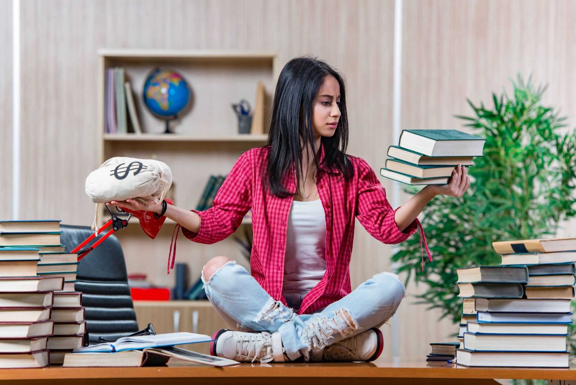 student holding a pile of books on one hand and some money on the other