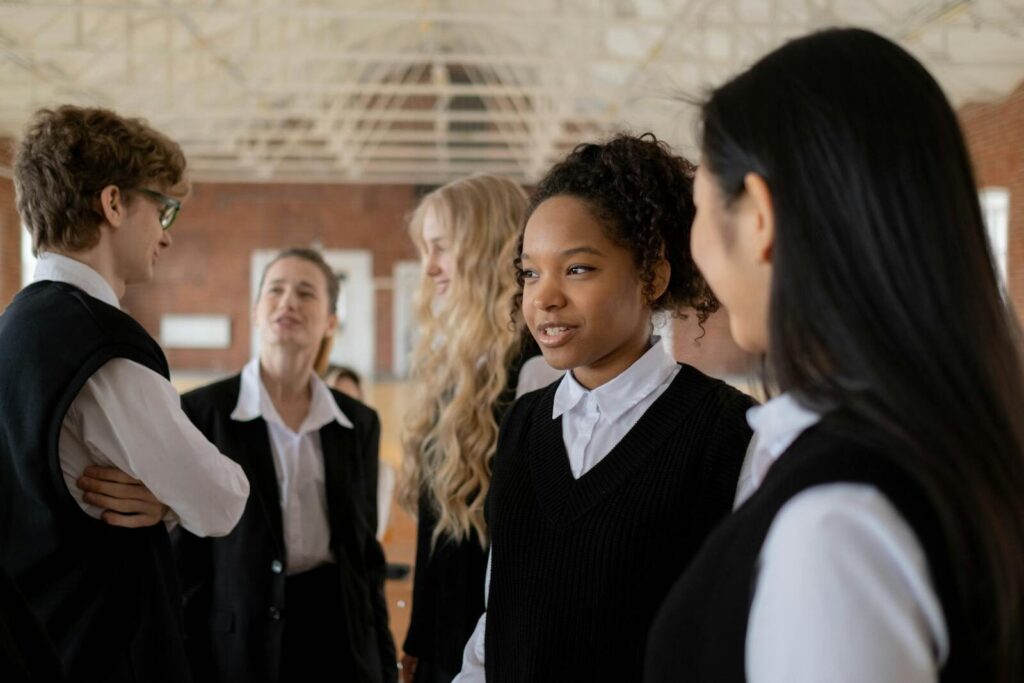 A diverse group of students in school uniforms having a conversation indoors.